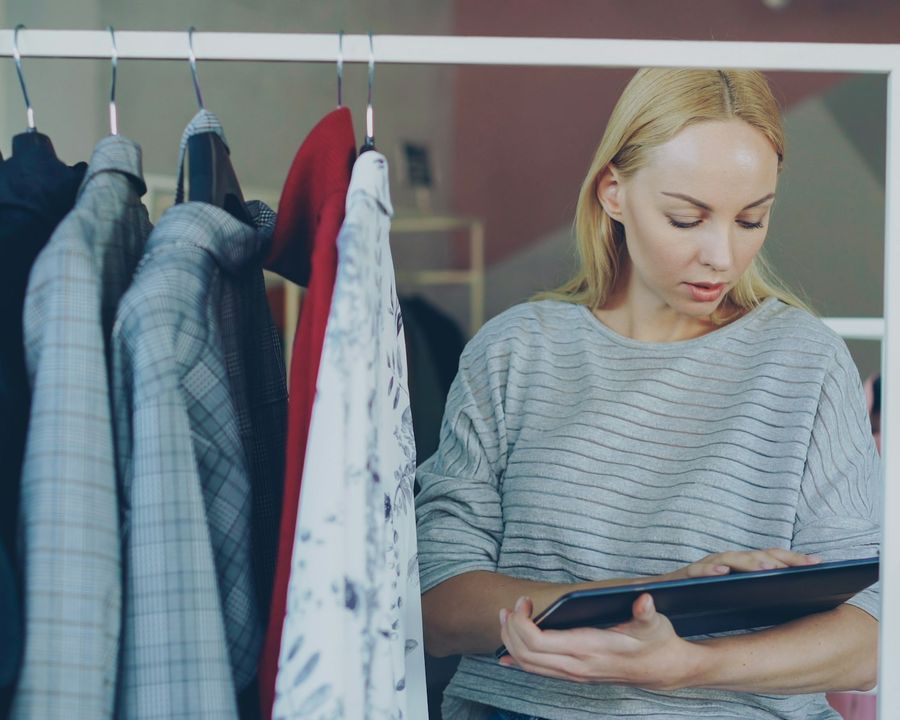 A clothing store owner checking stock on the rails with a tablet