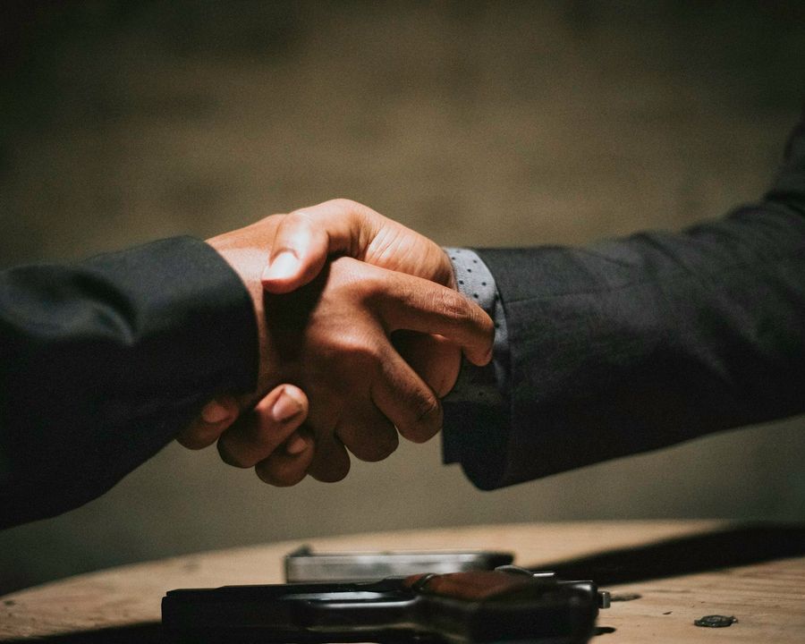 Two people shaking hands over a wooden table