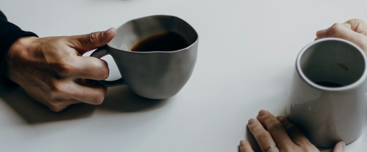 Two people chatting across a table with cups of coffee