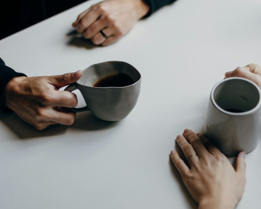 Two people chatting across a table with cups of coffee