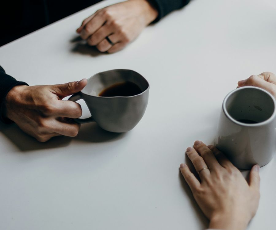 Two people chatting across a table with cups of coffee