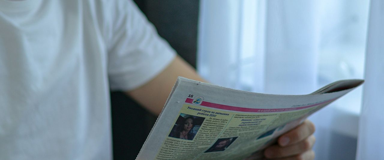 A man reading the morning paper over a cup of coffee at his table
