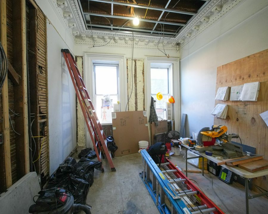 An interior under renovation with ladders, tools and exposed framing