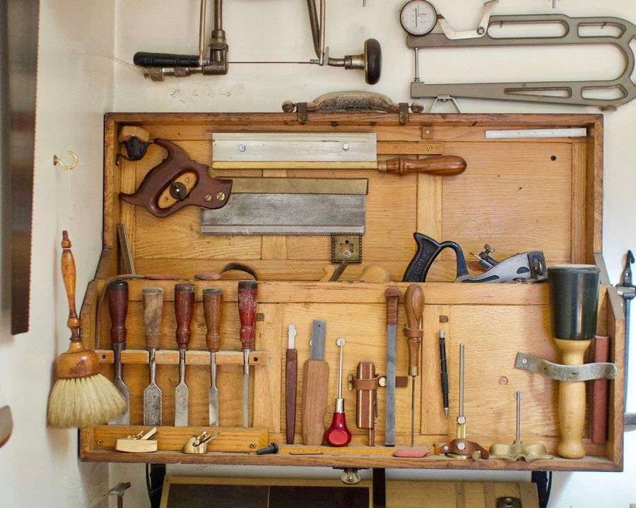 A tidy workbench covered with woodworking tools in a small workshop